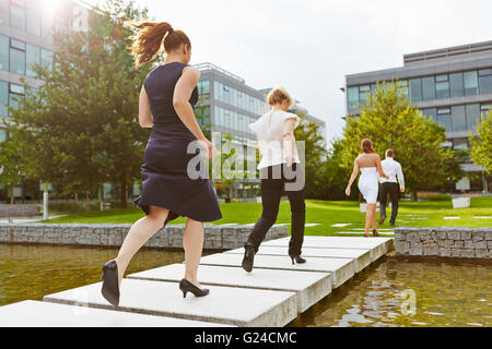 Viele Geschäftsleute, die über eine Brücke vor dem Büro Stockfoto