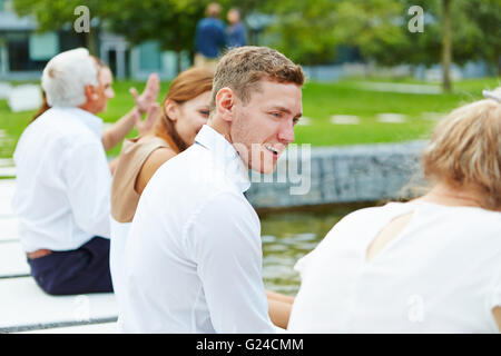 Glücklich Geschäftsleute sitzen an einem Teich im Sommer und miteinander zu reden Stockfoto