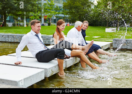 Glücklich Geschäftsleute Spritzwasser im Sommer mit ihren Füßen Stockfoto