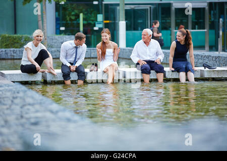 Glücklich Geschäftsleute sprechen während der Pause im Sommer mit den Füßen im Wasser Stockfoto