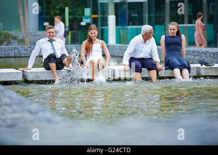 Lustige happy Geschäftsleute Spritzwasser mit ihren Füßen in einem See Stockfoto