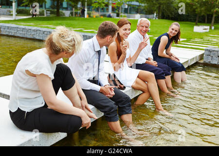 Business-Team im Sommer kühlen ihre Füße im Wasser während eines Treffens Stockfoto