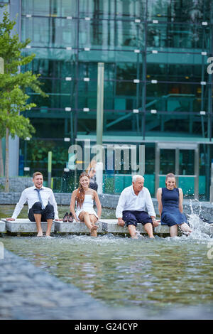 Business-Team Spritzwasser im Sommer mit ihren Füßen in einem See Stockfoto