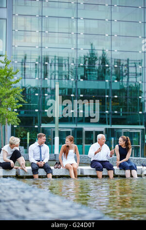 Entspannten Business-Team mit einem Treffen im Sommer mit Füßen im Wasser eines Sees Stockfoto