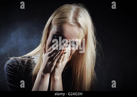 trauriges schockiert Mädchen weinend auf schwarzem Hintergrund Stockfoto