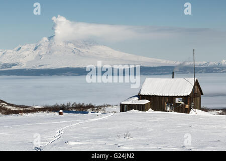 Blick auf den Bereich Holzhaus Kamtschatka Vulkanologen auf dem Hintergrund ausbrechenden Vulkan Shiveluch Inter. Stockfoto
