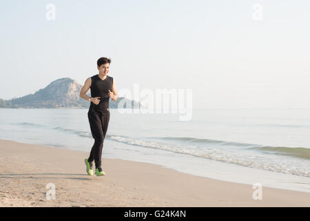 Asiatische junge Mann läuft allein am Strand morgens Stockfoto