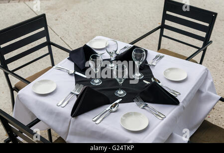 Bistro-Tisch und Stühle mit einer weißen Tischdecke und ausgefallene Gedecke. Stockfoto