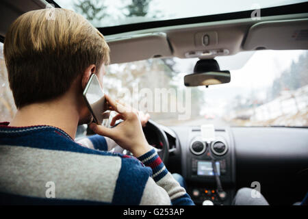 Rückansicht des jungen Menschen in gestreiften Pullover fahren und telefonieren mit Handy Stockfoto