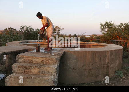 PRADHAN TRIBE - Mann Zeichnung Wasser aus Brunnen. Pradhan Boti, Kalam Taluka, Maharashtra in Indien Stockfoto