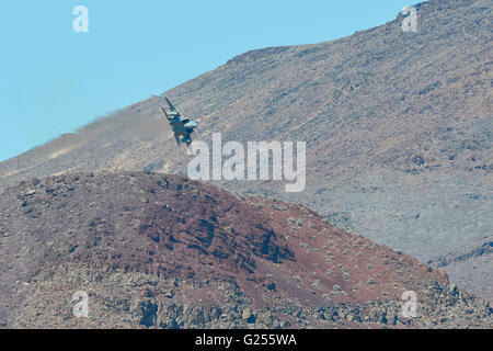 F-15 c Eagle Kampfjet fliegen durch eine Wüste Schlucht Kondensstreifen-Streaming von den Flügelspitzen. Stockfoto