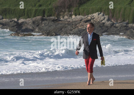 Ein elegant gekleideter Mann nimmt ein Abend Fistral Strand in Newquay, Cornwall entlang schlendert. Stockfoto