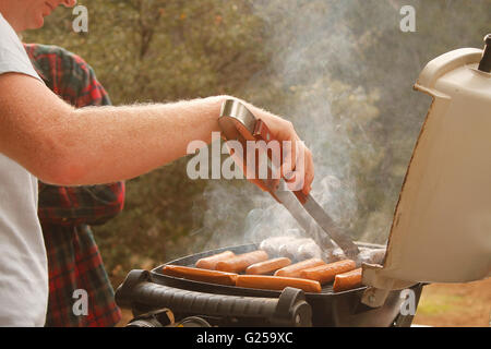 Mann, die Würstchen auf dem Grill kochen Stockfoto