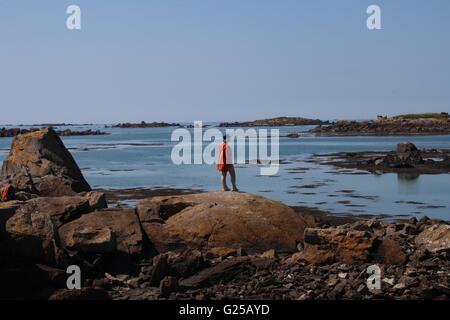 Frau steht auf Felsen, Blick auf das Meer, Chausey, Normandie, Frankreich Stockfoto