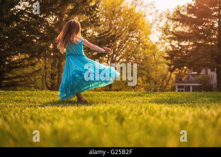 Mädchen im Garten drehen in einem Kleid Stockfoto