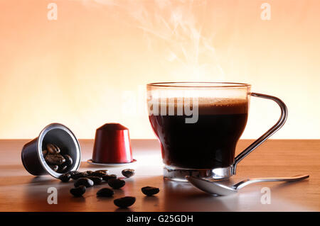 Kapseln und Tasse heißen Espresso auf einen Tisch und braunem Hintergrund Stockfoto