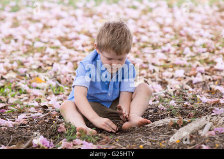 Kleiner Junge spielt mit Schmutz im Garten Stockfoto