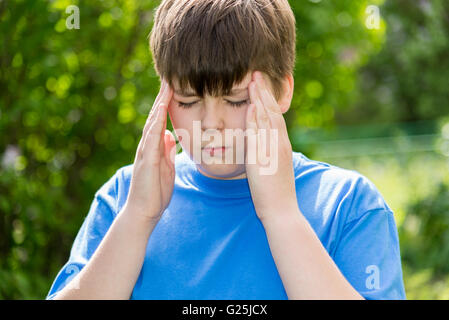 Junge Teenager mit Kopfschmerzen auf Natur Stockfoto