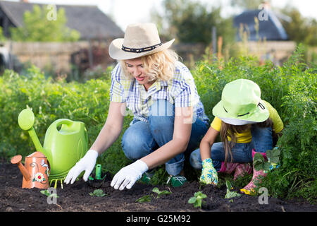 Gartenarbeit, Pflanzen - Mutter mit Tochter Kind Erdbeer Pflanzensämlinge ins Beet Stockfoto