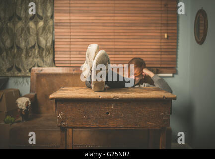 Eine junge Frau trägt Schuhe abgenutzt ist ihre Füße ruhen auf einem Tisch zu Hause Stockfoto