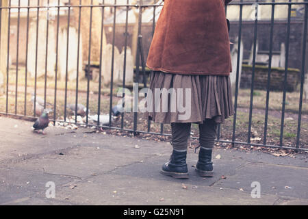 Eine Frau füttert einige Tauben auf einem Friedhof Stockfoto