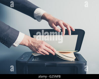 Die Hände eines jungen Geschäftsmann setzt ein Buch auf einen Flachbett-Scanner in Vorbereitung auf Kopieren Stockfoto