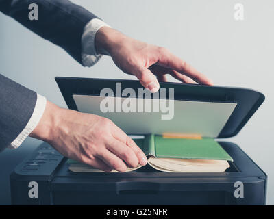 Die Hände eines jungen Geschäftsmann setzt ein Buch auf einen Flachbett-Scanner in Vorbereitung auf Kopieren Stockfoto