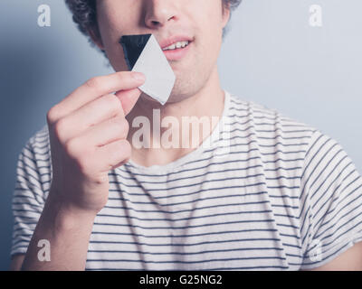 Ein junger Mann ist ein Stück Klebeband entfernen, die den Mund bezogen hat Stockfoto