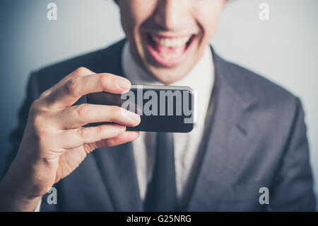 Ein glücklicher junge Geschäftsmann ist seine Smartphone verwenden. Stockfoto