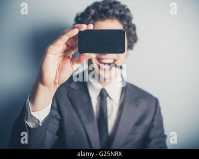 Ein junger Geschäftsmann ist eine Zigarre rauchend und nimmt ein Selbstporträt mit seinem smartphone Stockfoto
