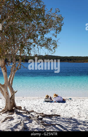 Paar liegen am Sandstrand neben Niaouli, breitblättrigen leichte (Melaleuca Quinquenervia), Lake McKenzie Stockfoto