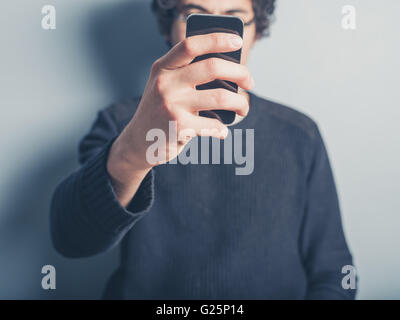 Ein junger Mann nimmt eine Selfie von sich selbst mit seinem smartphone Stockfoto