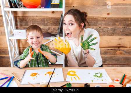 Lächelnd, kleiner Junge und seine Mutter Spaß und Hände zeigen lackiert in bunten Farben Stockfoto