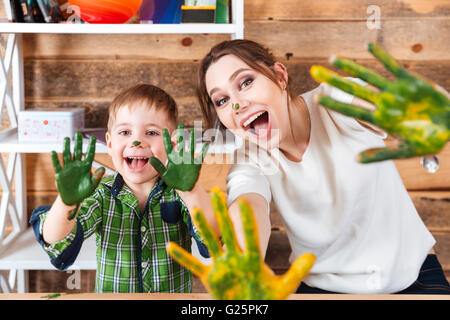 Lächelnd aufgeregt, kleinen Jungen und seiner Mutter zeigt Hände in bunten Farben bemalt und lachen Stockfoto