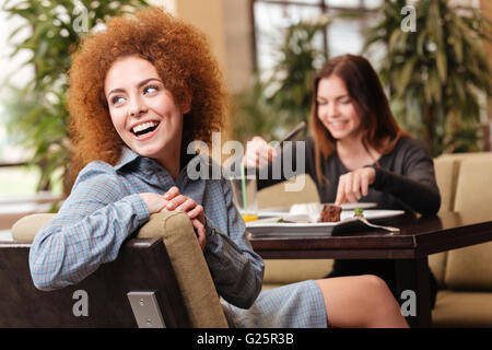 Zwei fröhliche schönen jungen Frauen im Café sitzen und gemeinsam lachen Stockfoto