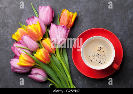 Frische Bunte Tulpen Blumen und Kaffeetasse auf dunklen Steintisch. Ansicht von oben Stockfoto