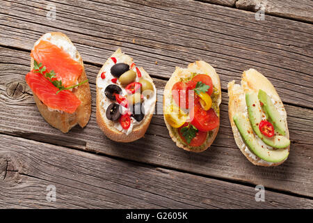 Toast-Sandwiches mit Avocado, Tomaten, Lachs und Oliven auf hölzernen Hintergrund. Ansicht von oben Stockfoto