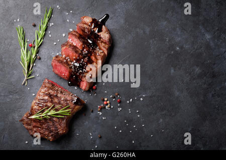 Gegrilltes Roastbeef in Scheiben geschnitten mit Salz und Pfeffer Steak über Steintisch. Draufsicht mit Textfreiraum Stockfoto