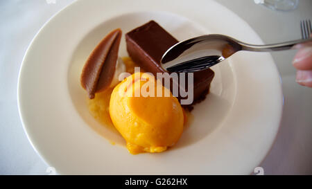 Gateau von dunkler Schokolade mit Kompott aus exotischen Früchten und Mango-Passionsfrucht-sorbet Stockfoto