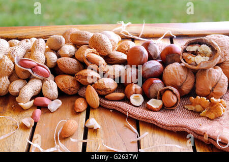 Gruppieren Sie leckere Nüssen in Schale und Schale auf einem Holztisch im Feld Stockfoto