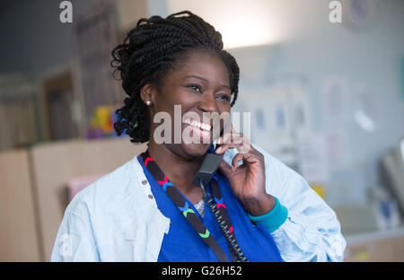 Krankenschwester, lächelnd und sprechen am Telefon in ihrer Gemeinde Stockfoto