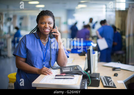 Krankenschwester an einer Workstation in einer Gemeinde, die Beantwortung von Anfragen und medizinische Unterlagen Stockfoto