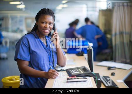 Krankenschwester an einer Workstation in einer Gemeinde, die Beantwortung von Anfragen und medizinische Unterlagen Stockfoto