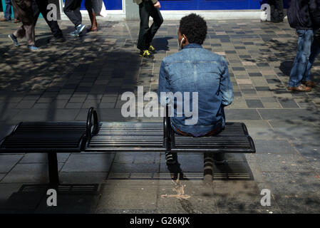 junge Afrikaner sitzen auf Bank mit Kopfhörer Glasgow, Scotland, UK. Stockfoto