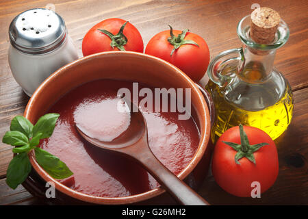 Tomatensauce auf einem Terrakotta-Topf mit Zutaten von oben gesehen. Stockfoto