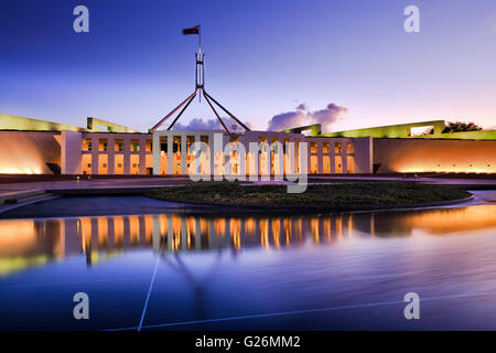 Australische nationale Parlamentsgebäude in Canberra. Fassade der Buidling hell erleuchtet und reflektiert in fließend Wasser Stockfoto