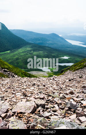 Gezackte Trümmer von Felsen Abstieg vom Berg gegen die grünen Hügeln verschwindende in weißen Nebel in Distanz, auf der Oberseite des Gros Morne. Stockfoto