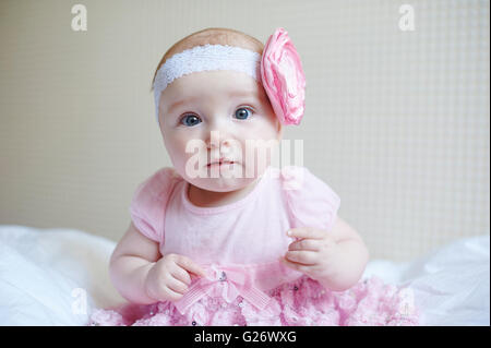 Schönen niedlichen Mädchen sitzt auf einem Bett in rosa Kleid Stockfoto