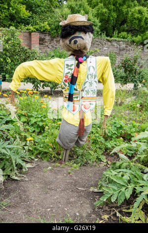Lustige Vogelscheuche im gelben Hemd und Weste schützt die Pflanzen im Garten Stockfoto