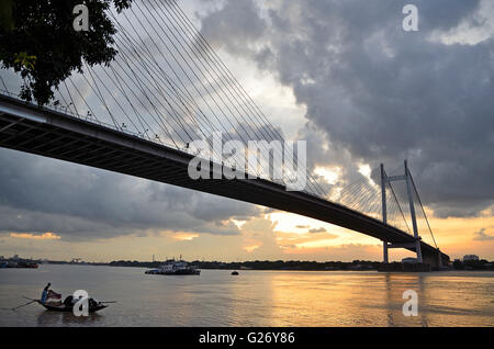 Regen Wolken schweben über zweite Hooghly Brücke bei Sonnenuntergang mit Land Angeln Boote schwimmen im Fluss unten, Kolkata, Westbengalen Stockfoto